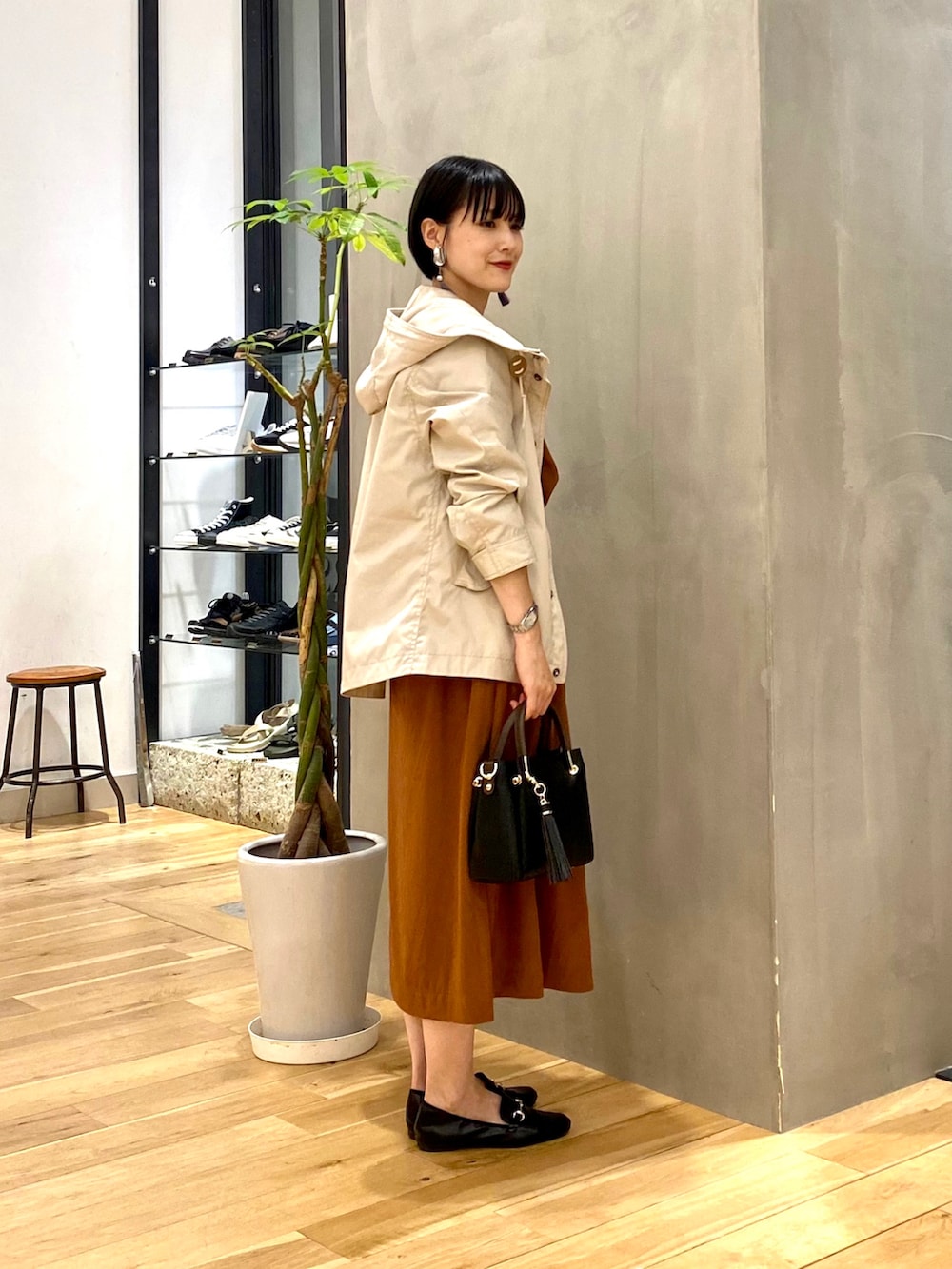 ベージュ系のマウンテンパーカー、イエロー系のワンピース、ブラック系のトートバッグを着用したレディースの秋コーディネートの2枚目の写真