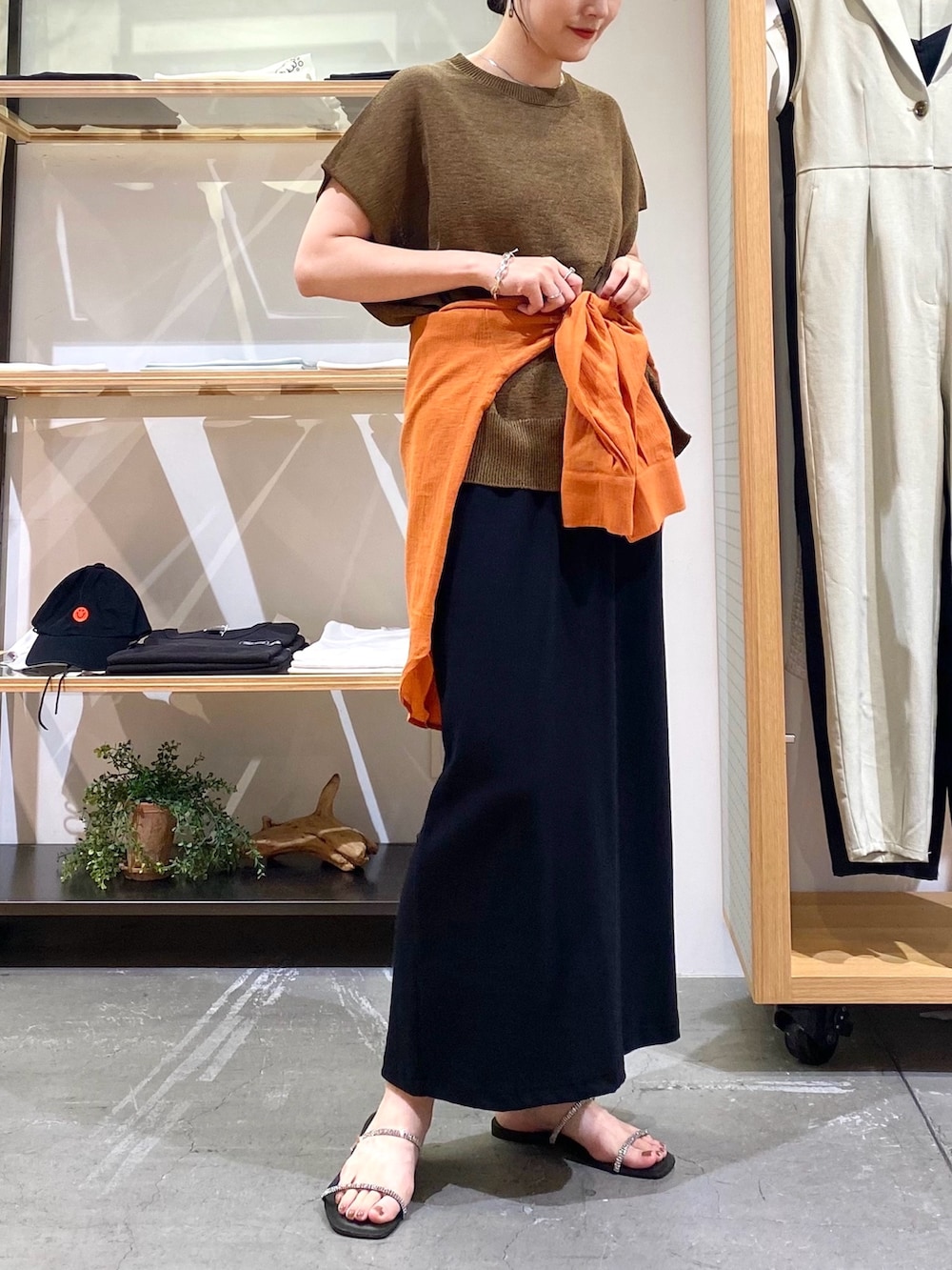 ブラウン系のニット/セーター、オレンジ系のシャツ/ブラウス、ブラック系のスカートを着用したレディースの夏コーディネートの7枚目の写真