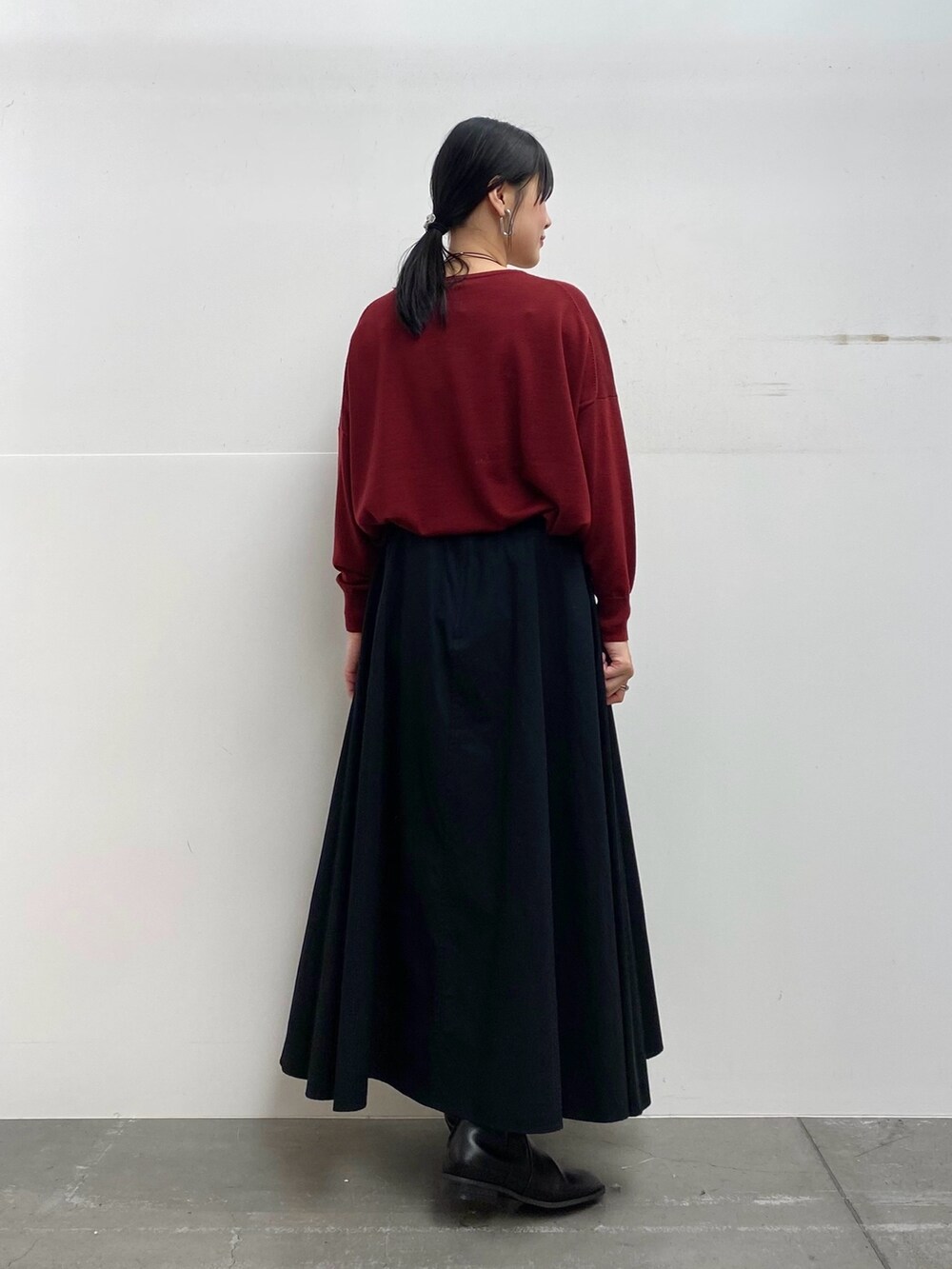 グレー系のステンカラーコート、レッド系のニット/セーター、ブラック系のスカートを着用したレディースの秋コーディネートの6枚目の写真