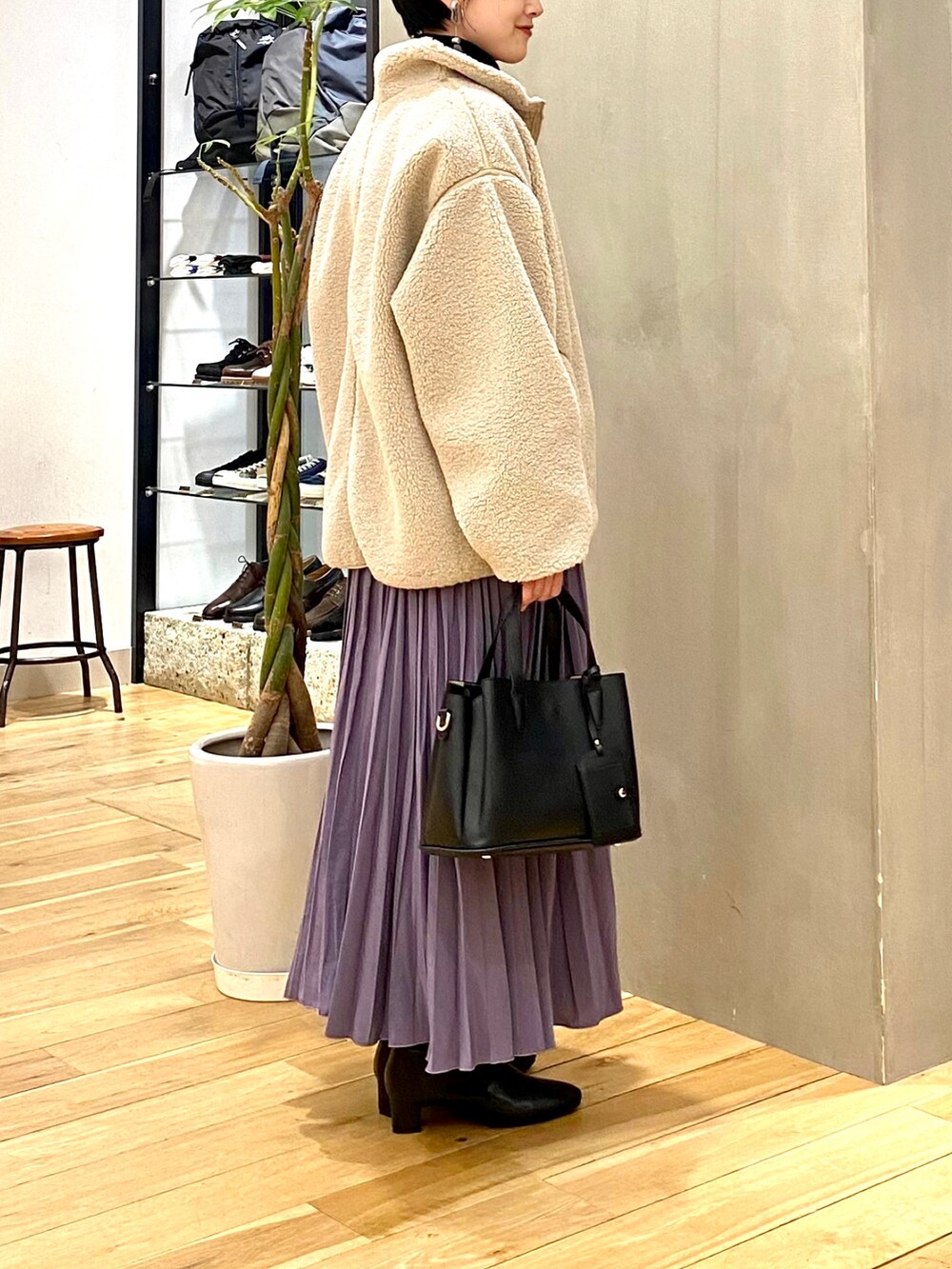 ホワイト系のブルゾン、ブラック系のニット/セーター、パープル系のスカートを着用したレディースの冬コーディネートの5枚目の写真