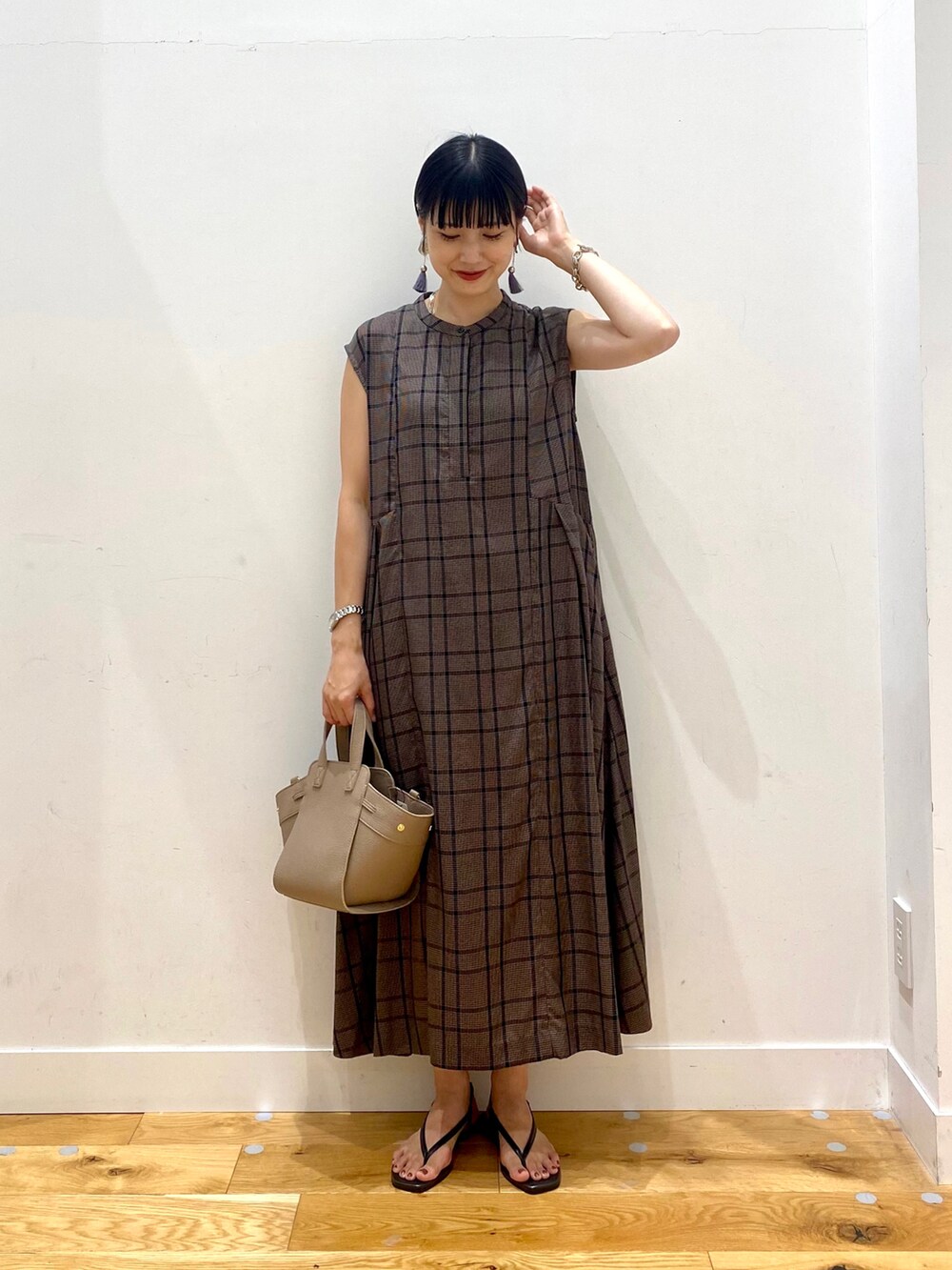 ブラウン系のワンピース、ブラウン系のハンドバッグ、ブラック系のサンダルを着用したレディースの夏コーディネートの2枚目の写真