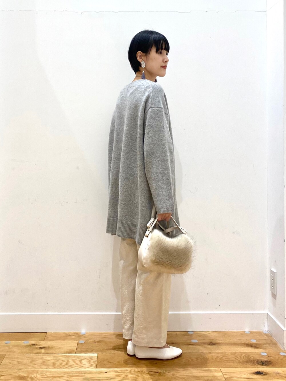 ブルー系のチェスターコート、グレー系のニット/セーター、ホワイト系のその他パンツを着用したレディースの冬コーディネートの5枚目の写真
