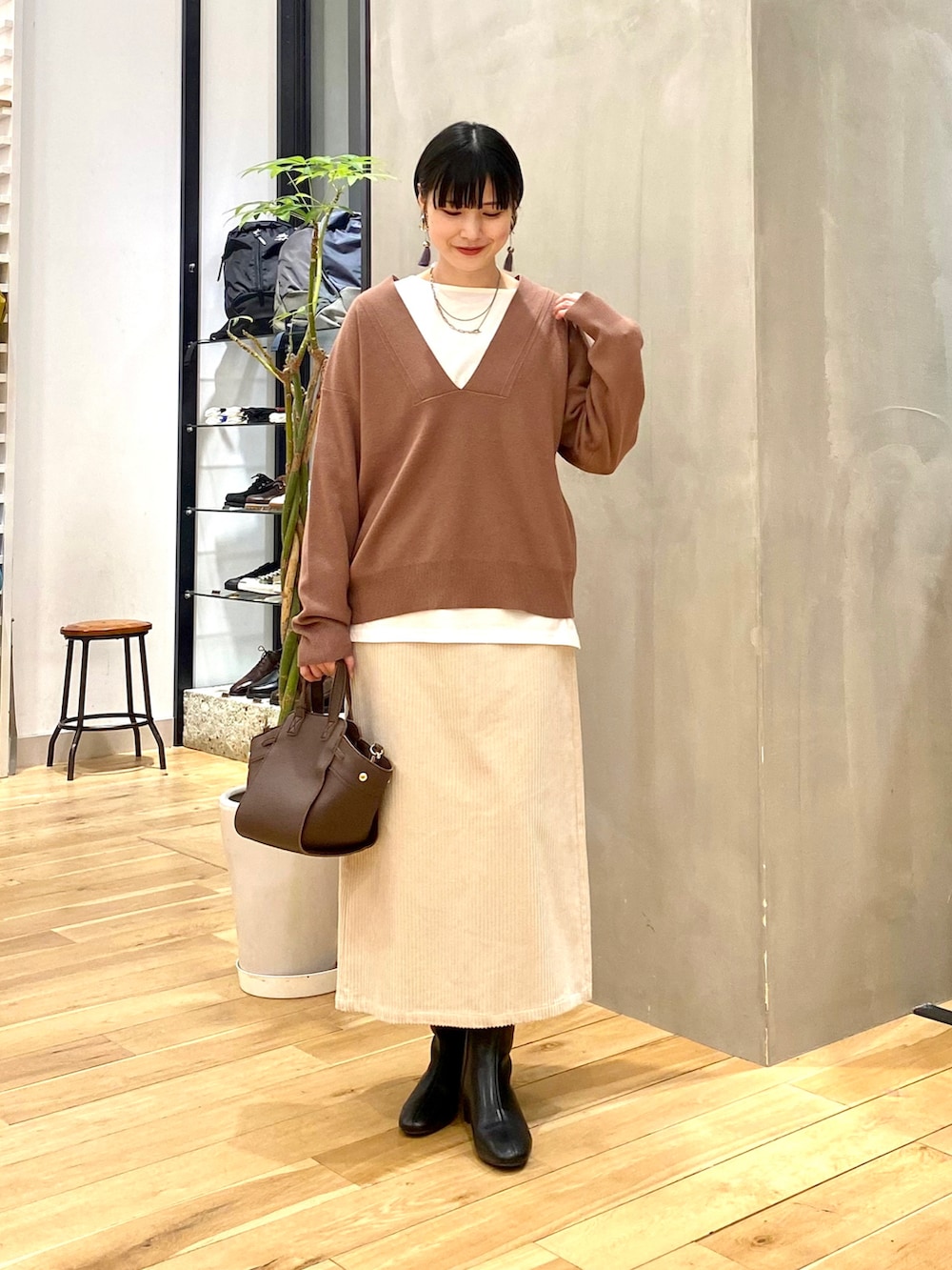 ブラウン系のニット/セーター、ホワイト系のTシャツ/カットソー、ホワイト系のスカートを着用したレディースの冬コーディネートの2枚目の写真