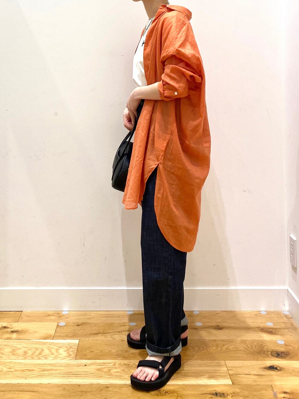 オレンジ系のシャツ/ブラウス、ホワイト系のTシャツ/カットソー、ブルー系のデニムパンツを着用したレディースの春コーディネートの5枚目の写真