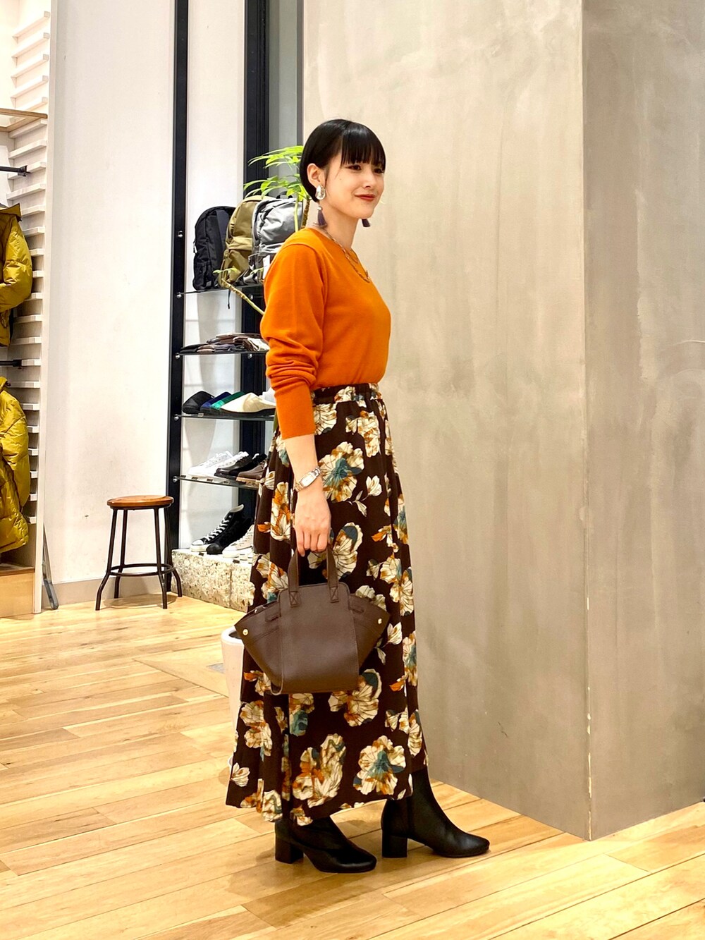 ベージュ系のダウンジャケット/コート、オレンジ系のニット/セーター、ブラウン系のスカートを着用したレディースの秋コーディネートの4枚目の写真