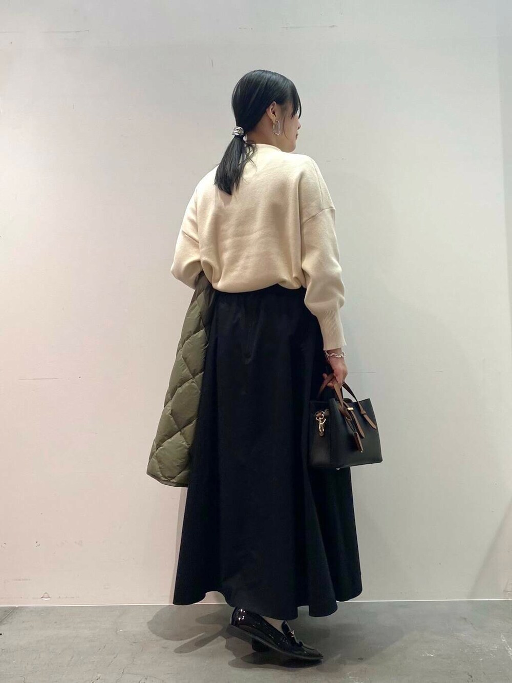 ブラック系のハンドバッグ、グリーン系のダウンジャケット/コート、ブラック系のローファーを着用したレディースの秋コーディネートの6枚目の写真