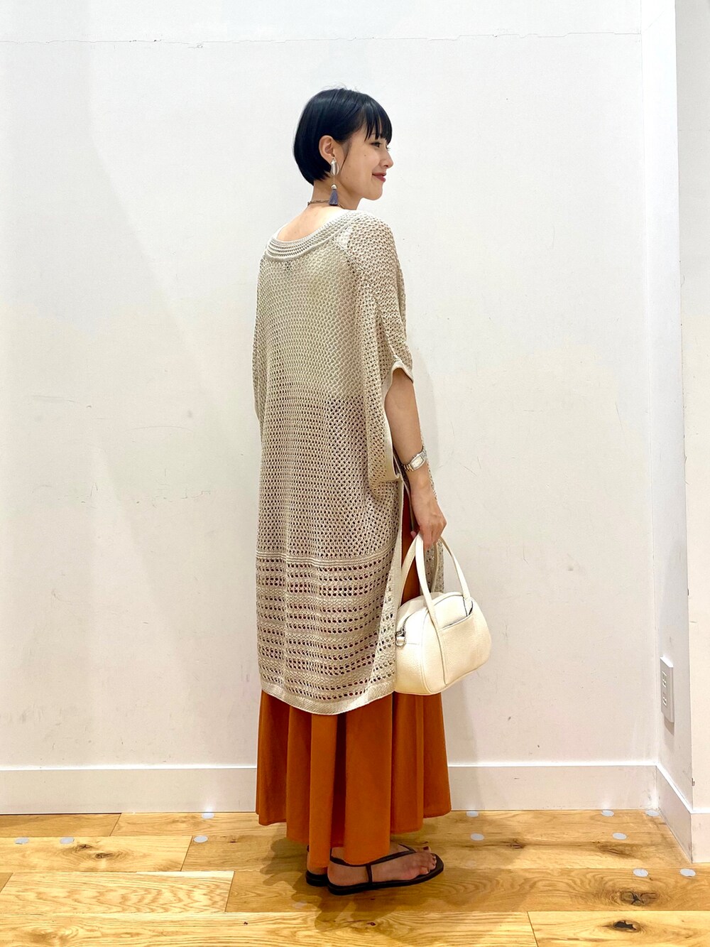ベージュ系のニット/セーター、ホワイト系のタンクトップ、オレンジ系のスカートを着用したレディースの夏コーディネートの3枚目の写真