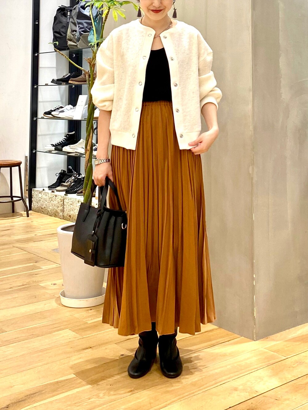 ホワイト系のカーディガン/ボレロ、ブラック系のタンクトップ、イエロー系のスカートを着用したレディースの秋コーディネートの4枚目の写真