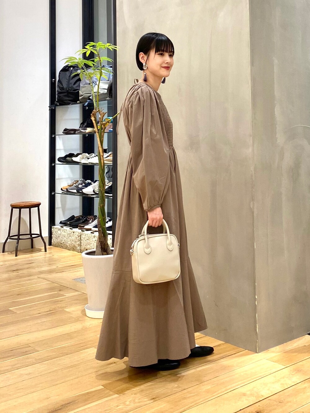 ブルー系のマウンテンパーカー、ブラウン系のワンピース、ベージュ系のショルダーバッグを着用したレディースの春コーディネートの4枚目の写真