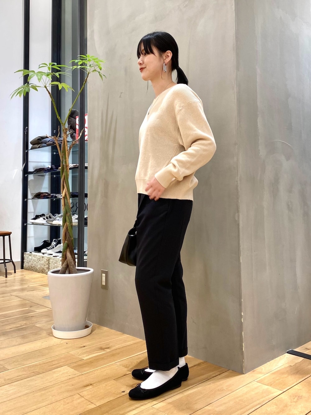 グリーン系のステンカラーコート、ホワイト系のニット/セーター、ブラック系のその他パンツを着用したレディースの冬コーディネートの6枚目の写真