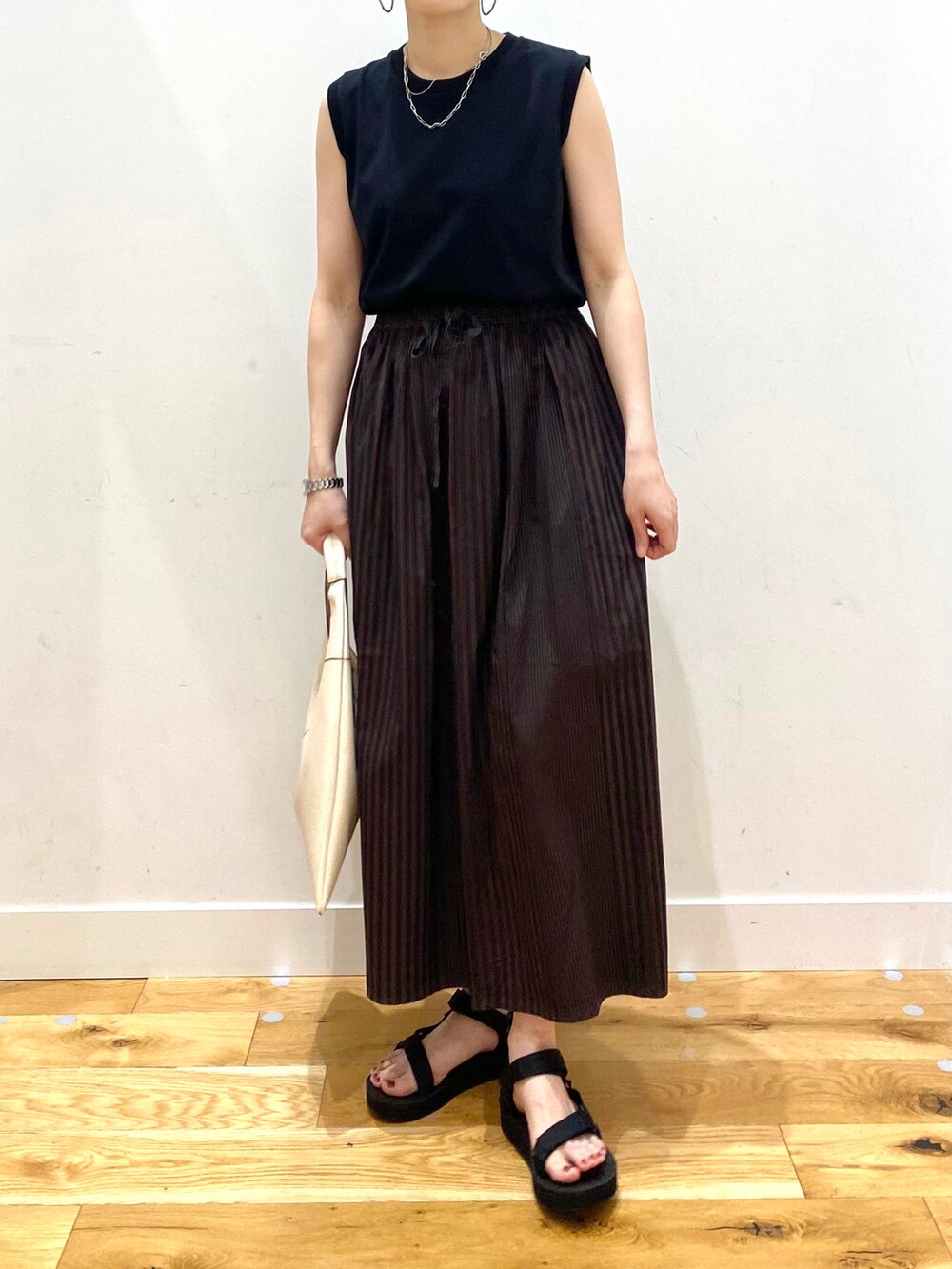 ブラック系のTシャツ/カットソー、ブラウン系のスカート、ホワイト系のトートバッグを着用したレディースの春コーディネートの4枚目の写真