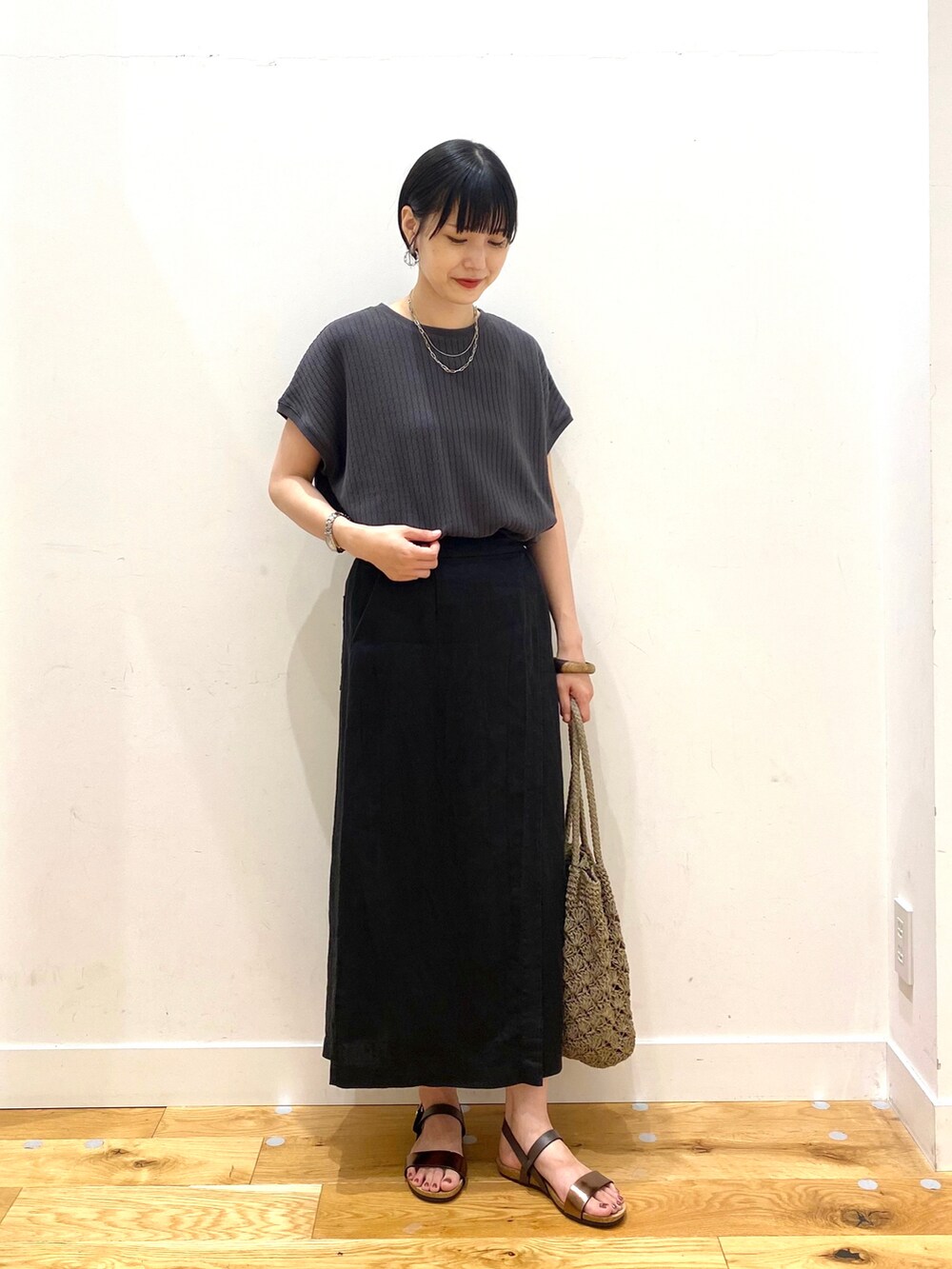 グレー系のTシャツ/カットソー、ブラック系のスカート、グレー系のトートバッグを着用したレディースの夏コーディネートの2枚目の写真