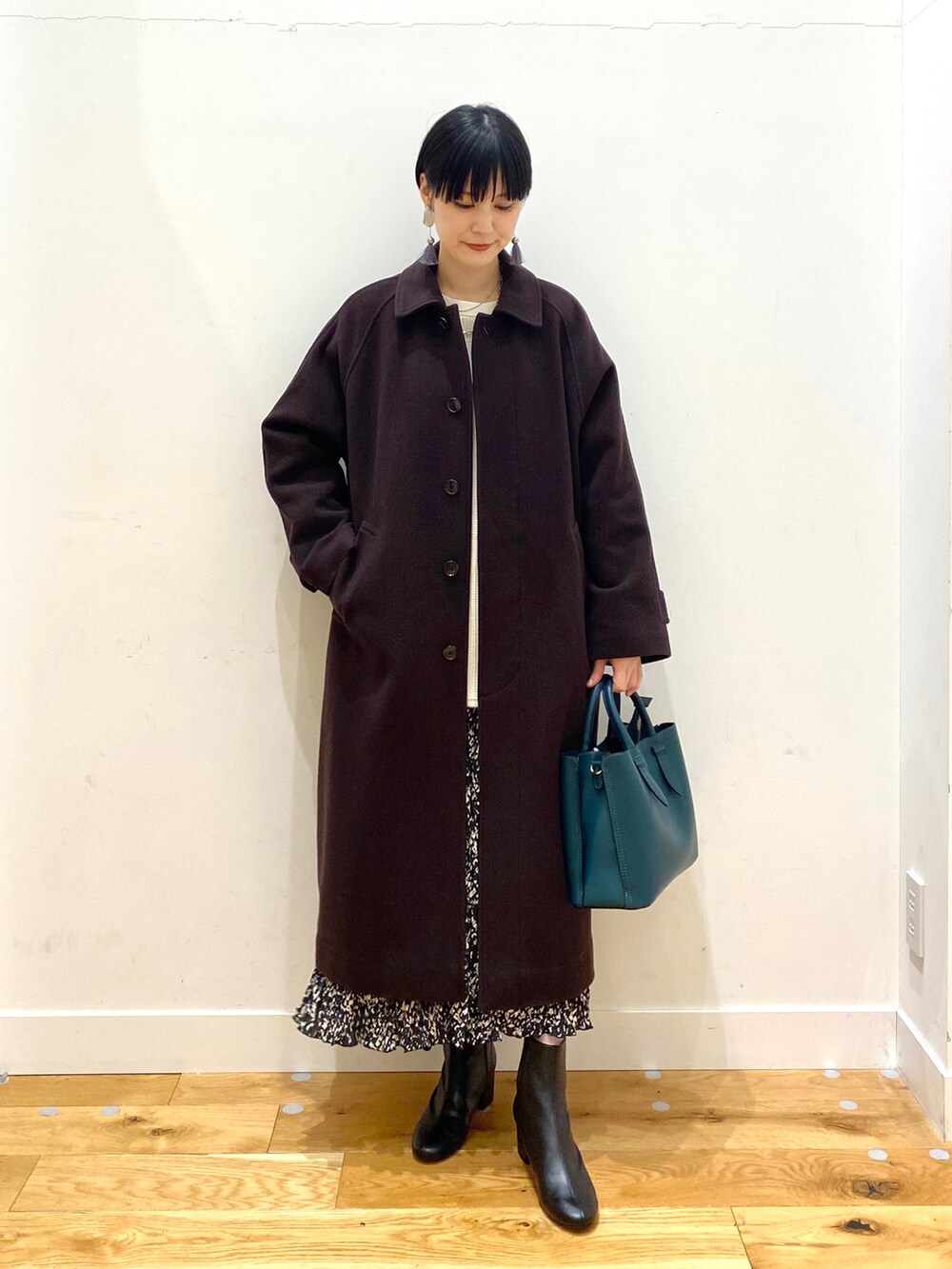 ブラウン系のステンカラーコート、ホワイト系のTシャツ/カットソー、ブラック系のスカートを着用したレディースの冬コーディネートの2枚目の写真