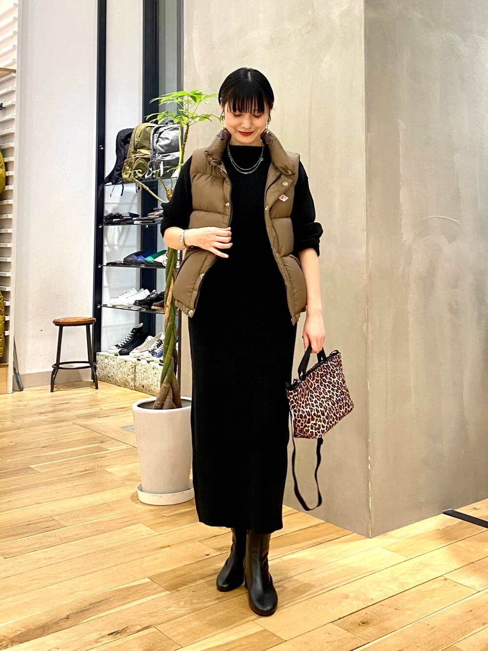 ベージュ系のダウンベスト、ブラック系のワンピース、その他のショルダーバッグを着用したレディースの秋コーディネートの2枚目の写真