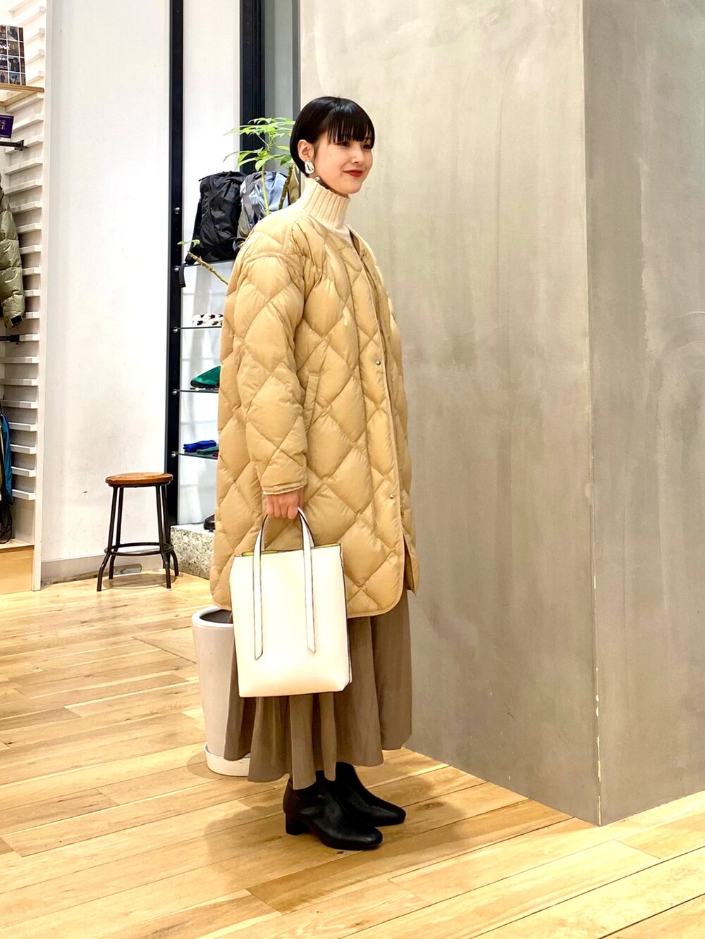 ベージュ系のダウンジャケット/コート、ホワイト系のニット/セーター、ブラウン系のスカートを着用したレディースの冬コーディネートの2枚目の写真