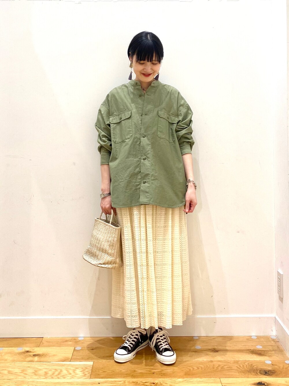 グリーン系のシャツ/ブラウス、ホワイト系のスカート、ブラック系のスニーカーを着用したレディースの春コーディネートの2枚目の写真