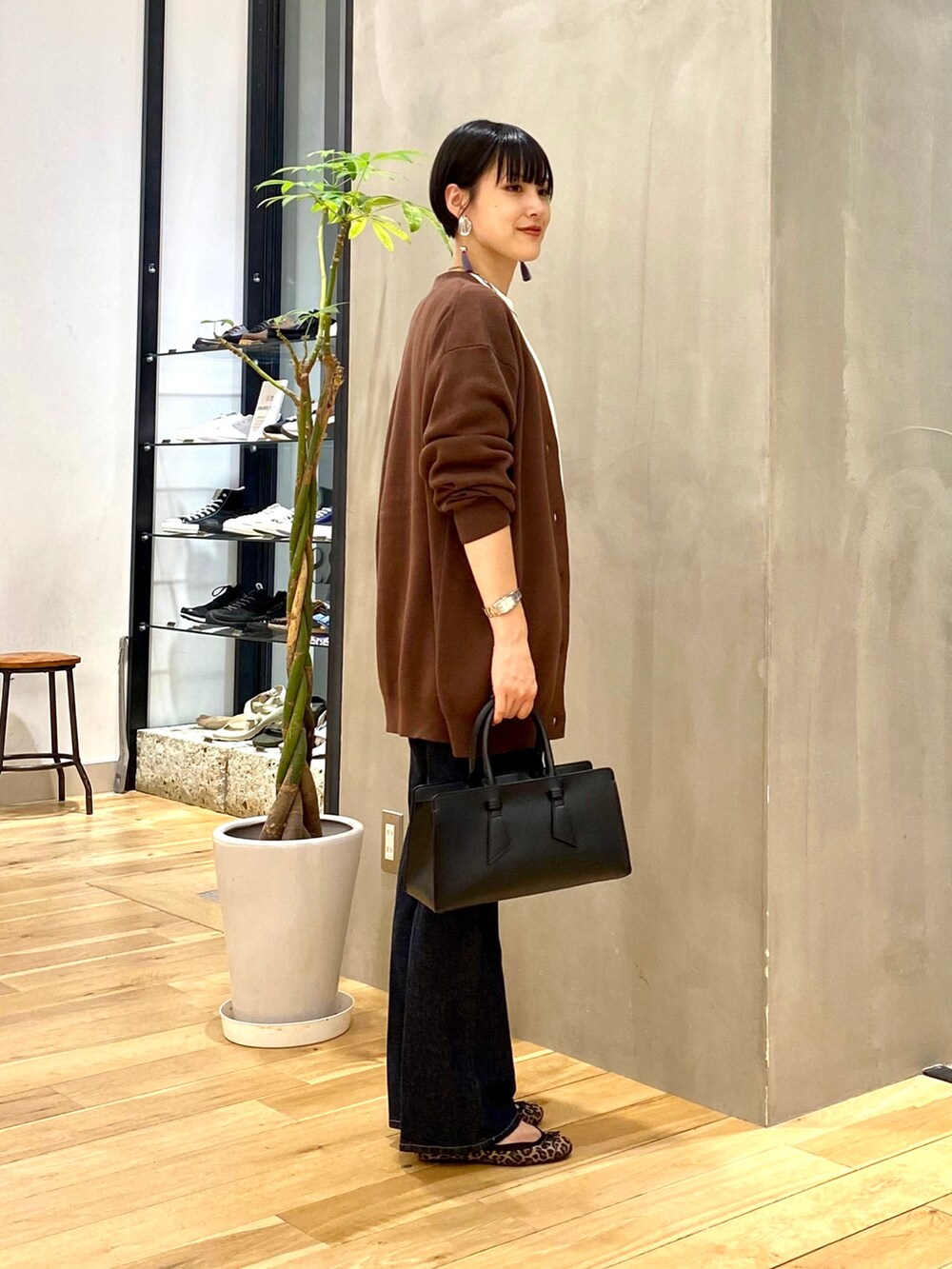 ブラウン系のカーディガン/ボレロ、ホワイト系のTシャツ/カットソー、ブルー系のデニムパンツを着用したレディースの秋コーディネートの2枚目の写真