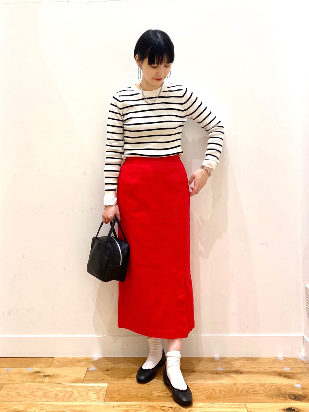ホワイト系のニット/セーター、レッド系のスカート、ブラック系のトートバッグを着用したレディースの冬コーディネートの2枚目の写真