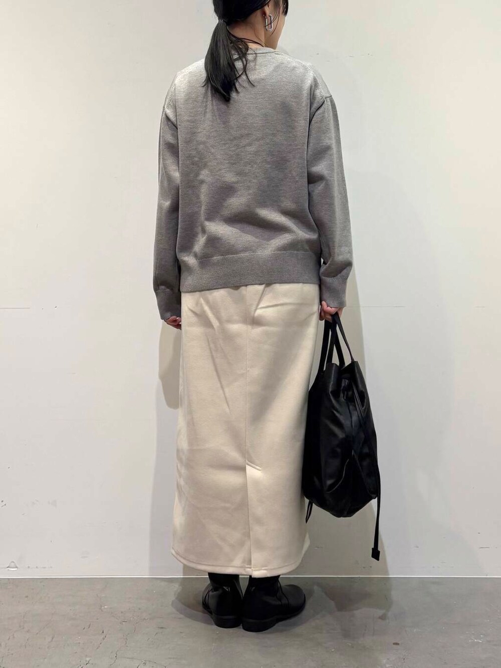 ブラック系のトートバッグ、ブラック系のブーツ、ホワイト系のスカートを着用したレディースの冬コーディネートの5枚目の写真