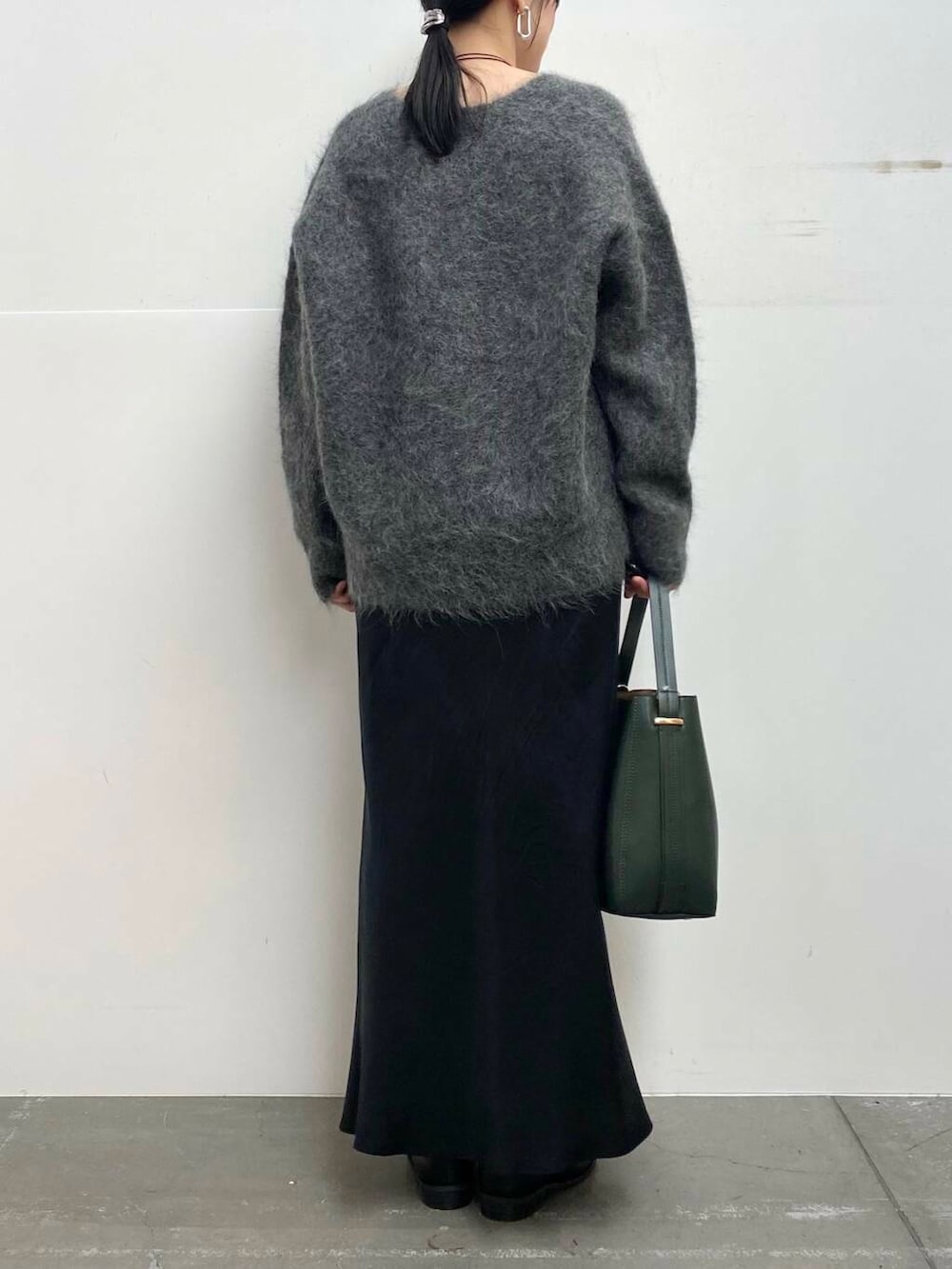 グリーン系のハンドバッグ、ブラック系のブーツ、ブラック系のスカートを着用したレディースの冬コーディネートの6枚目の写真