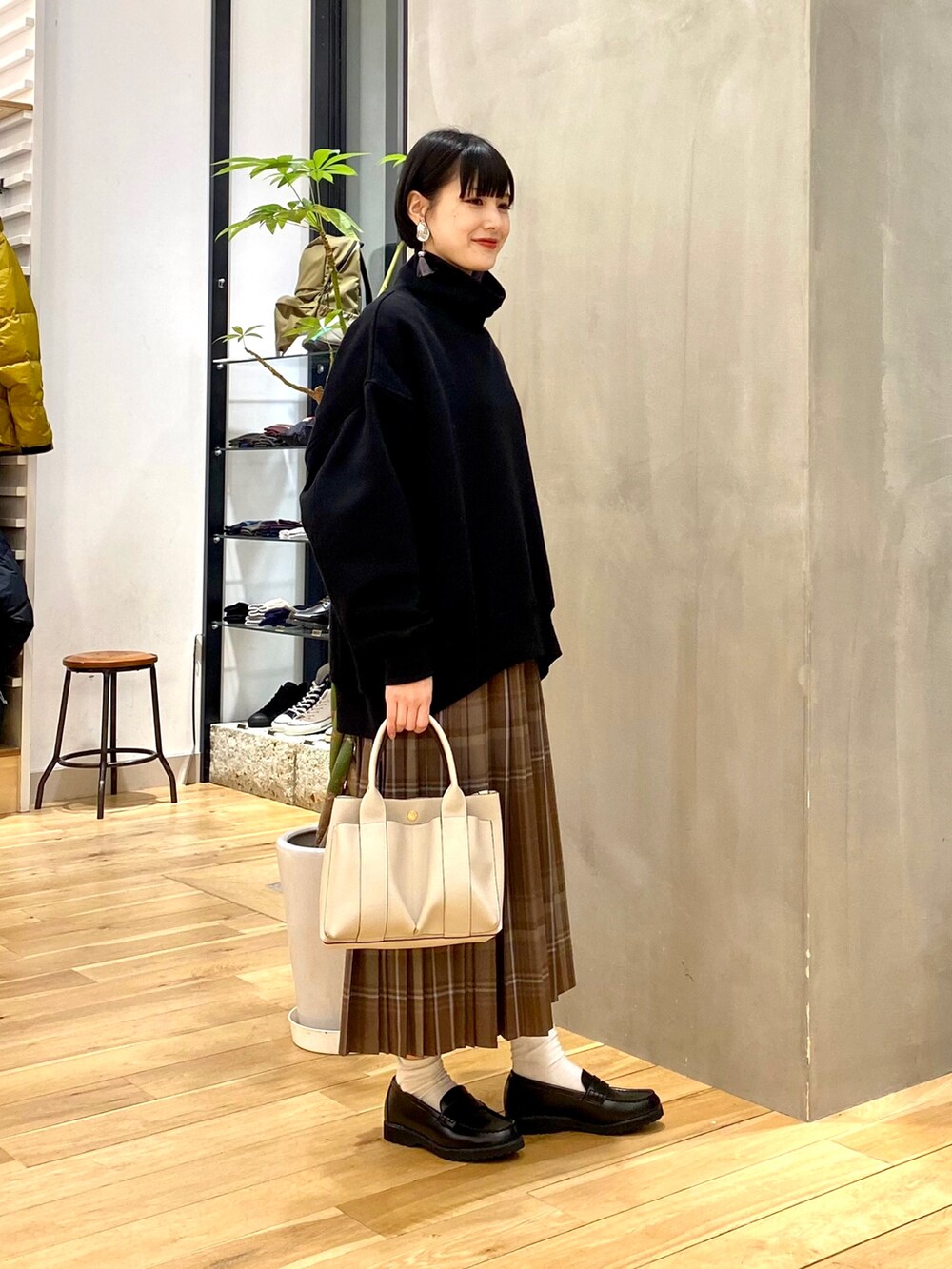 ブラック系のスウェット、ブラウン系のスカート、ホワイト系のトートバッグを着用したレディースの冬コーディネートの3枚目の写真