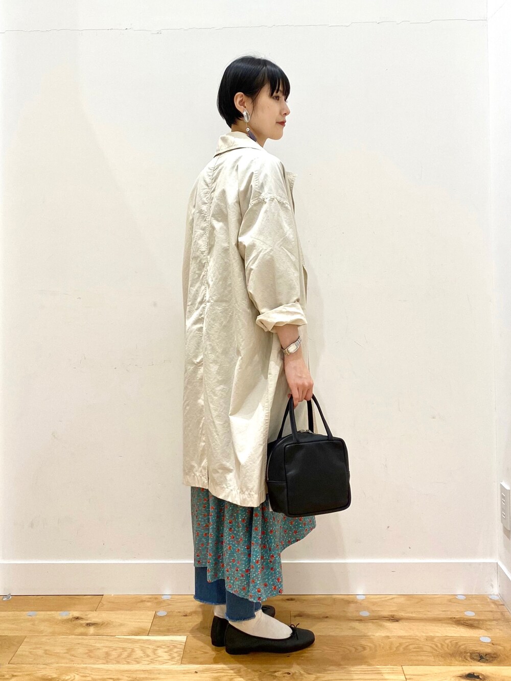 ホワイト系のチェスターコート、グリーン系のワンピース、ブルー系のデニムパンツを着用したレディースの冬コーディネートの5枚目の写真