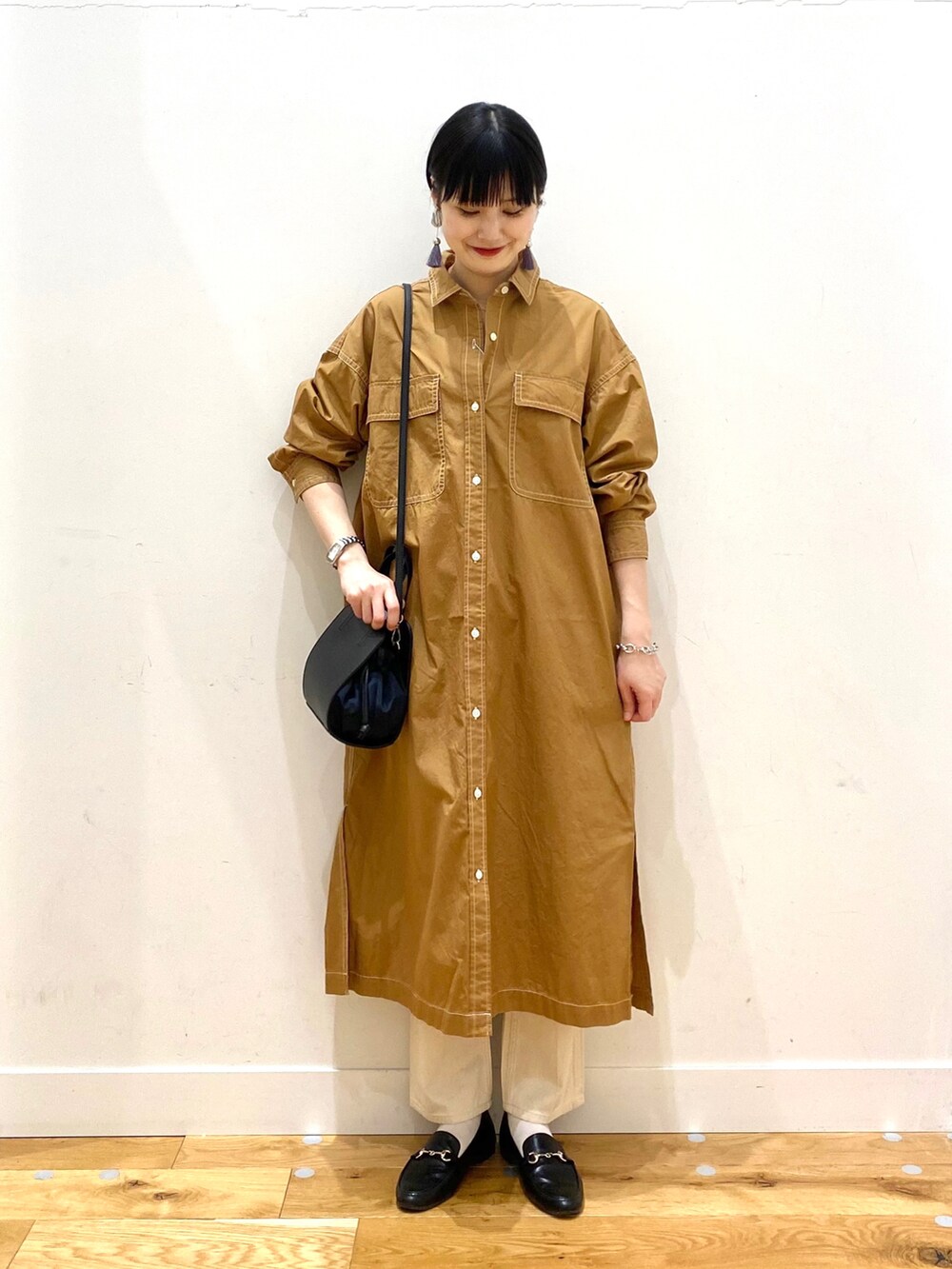 イエロー系のワンピース、ベージュ系のデニムパンツ、ブラック系のショルダーバッグを着用したレディースの春コーディネートの2枚目の写真