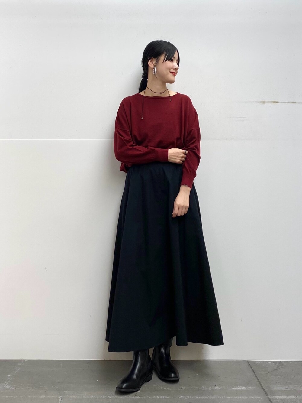 グレー系のステンカラーコート、レッド系のニット/セーター、ブラック系のスカートを着用したレディースの秋コーディネートの4枚目の写真