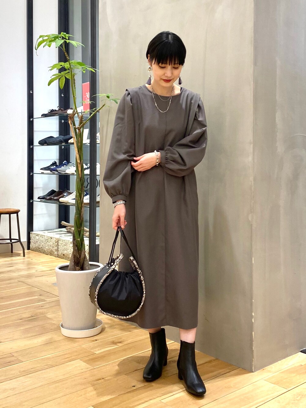 グレー系のワンピース、ブラック系のショルダーバッグ、ブラック系のブーツを着用したレディースの冬コーディネートの4枚目の写真