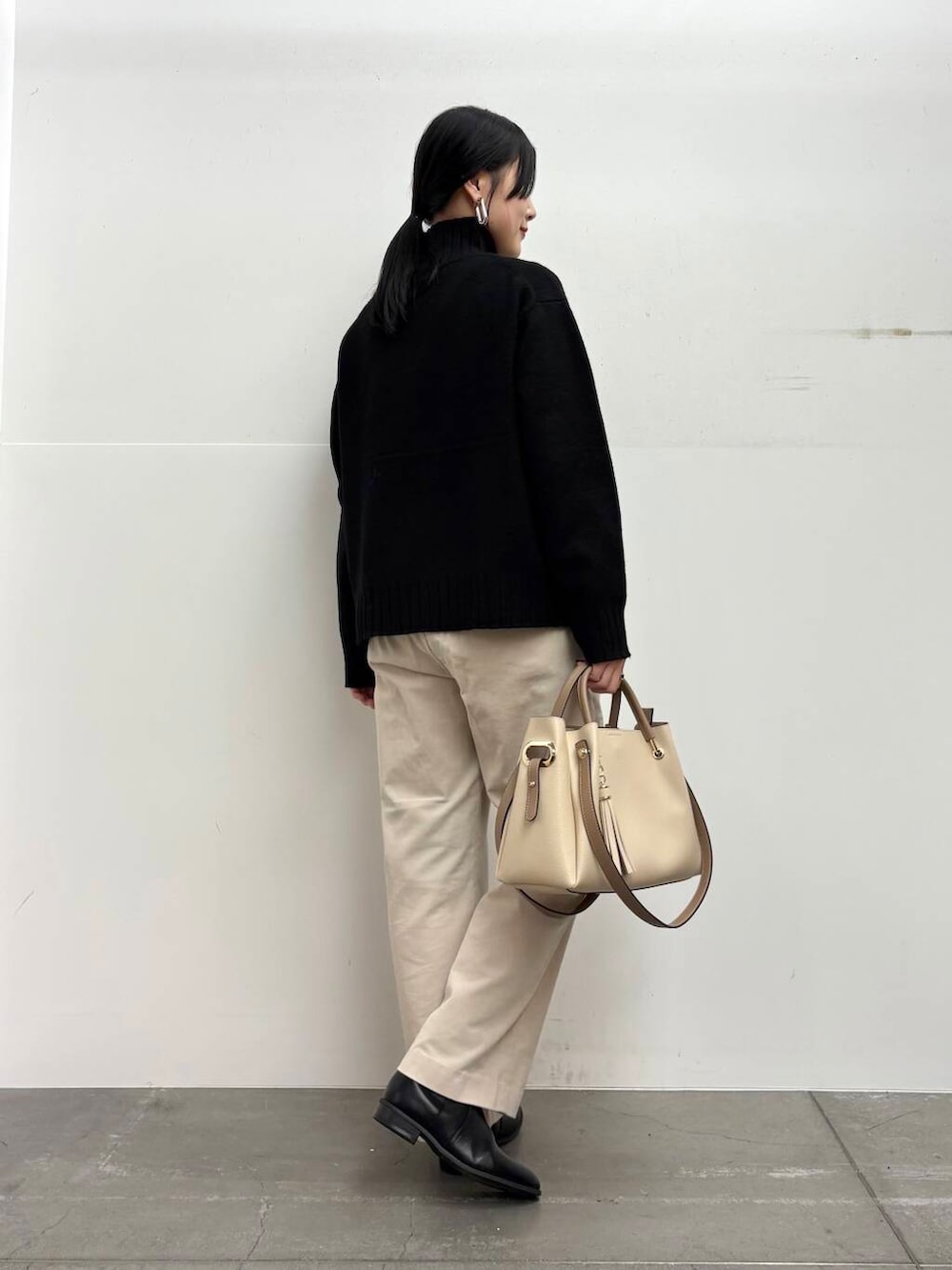 ホワイト系のトートバッグ、ブラック系のブーツ、ホワイト系のその他パンツを着用したレディースの冬コーディネートの3枚目の写真