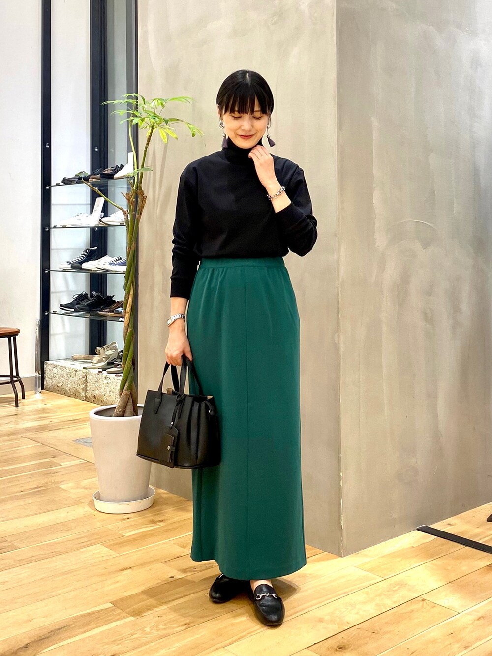 ホワイト系のノーカラージャケット、ブラック系のTシャツ/カットソー、グリーン系のスカートを着用したレディースの秋コーディネートの3枚目の写真