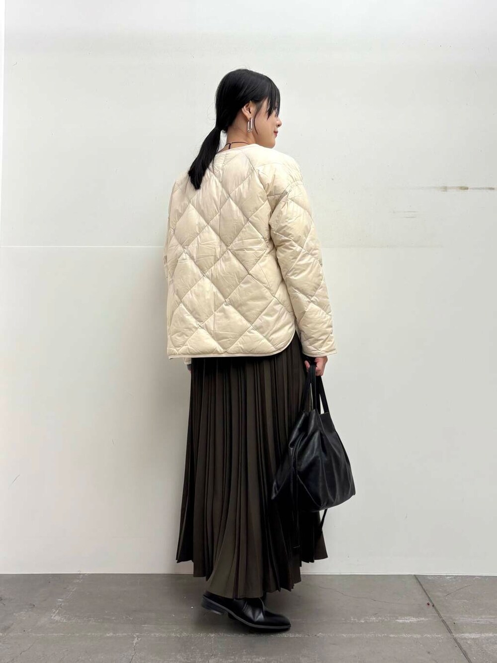 ブラック系のショルダーバッグ、ホワイト系のダウンジャケット/コート、ブラック系のブーツを着用したレディースの冬コーディネートの3枚目の写真