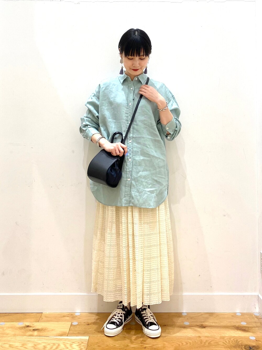 グリーン系のシャツ/ブラウス、ホワイト系のスカート、ブラック系のショルダーバッグを着用したレディースの春コーディネートの2枚目の写真