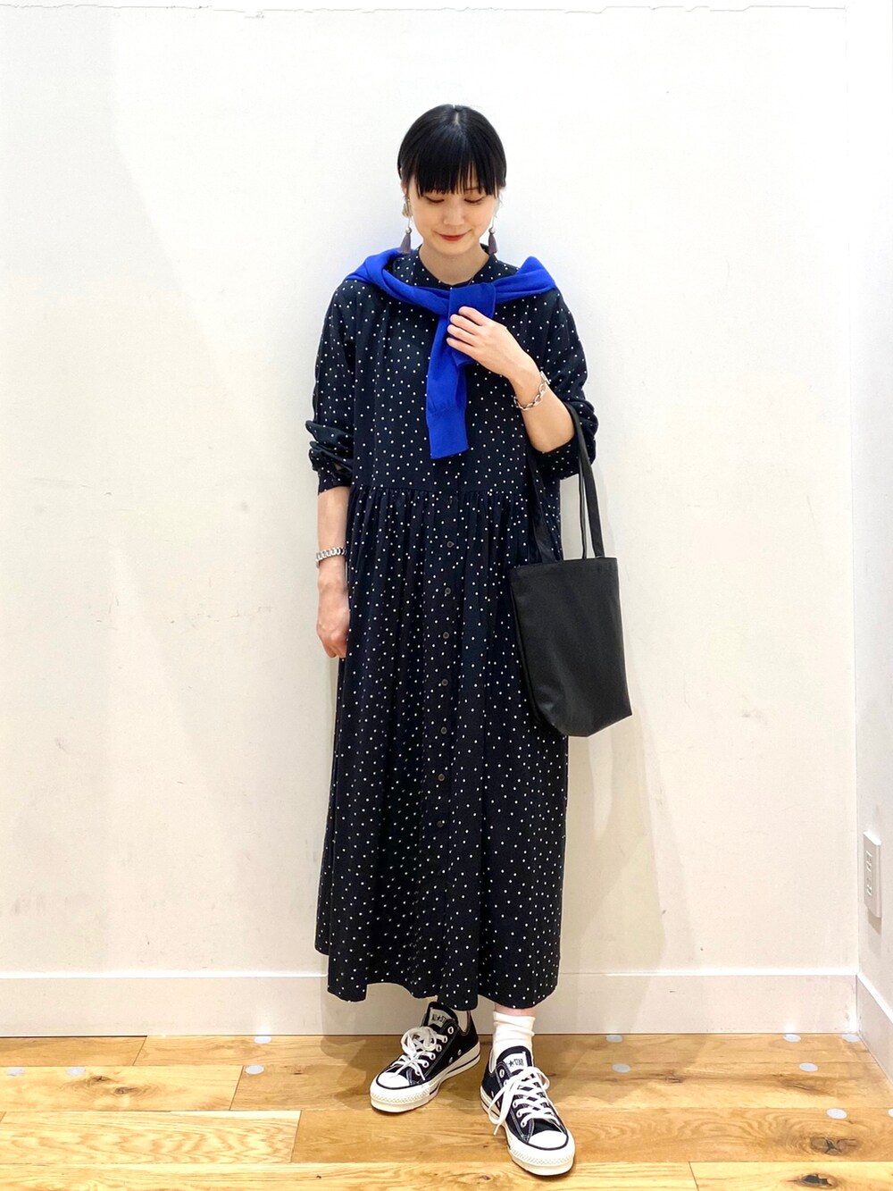 ブラック系のワンピース、ブルー系のカーディガン/ボレロ、ブラック系のトートバッグを着用したレディースの春コーディネートの2枚目の写真