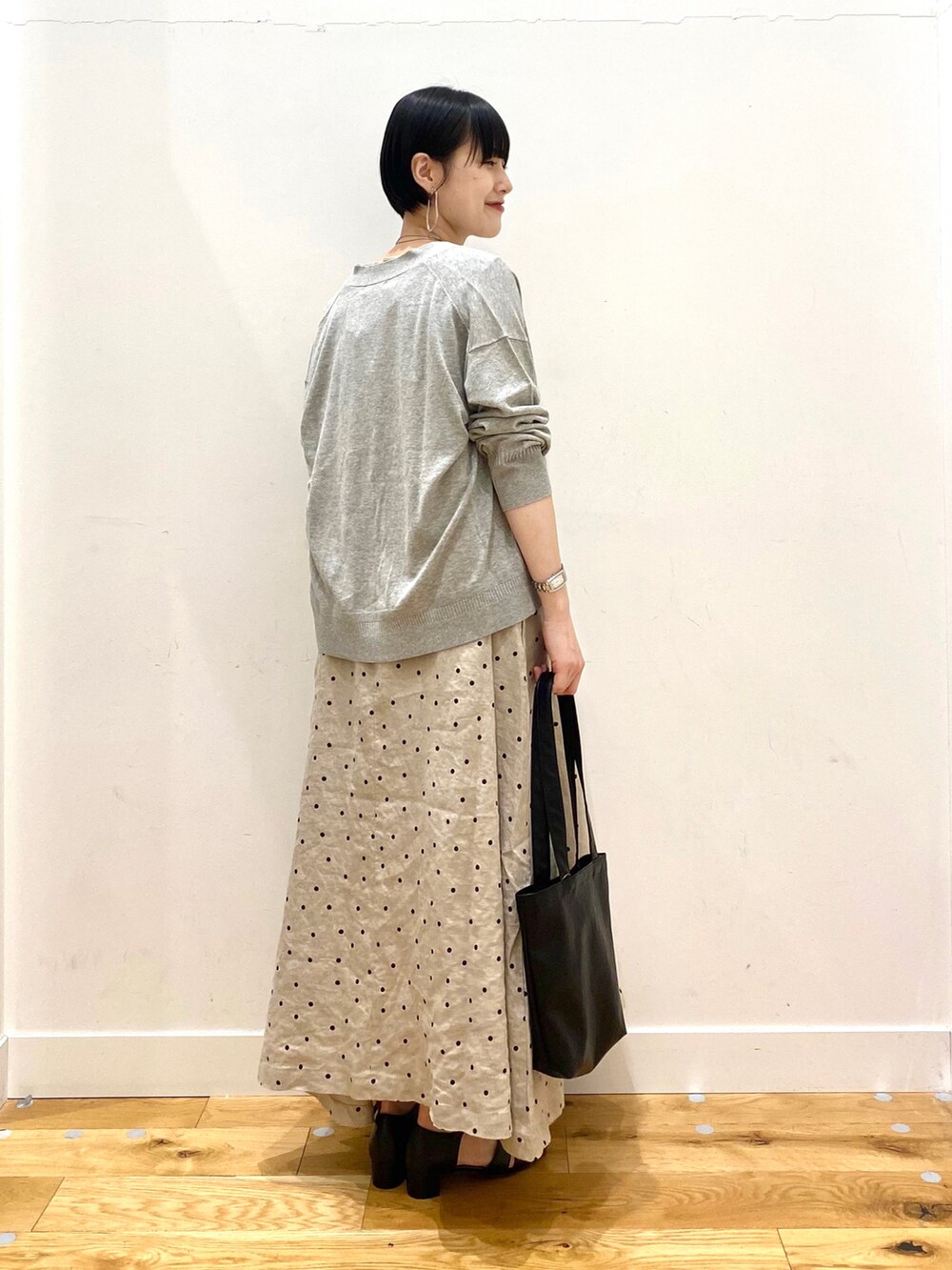 グレー系のカーディガン/ボレロ、ベージュ系のワンピース、ブラック系のトートバッグを着用したレディースの春コーディネートの2枚目の写真