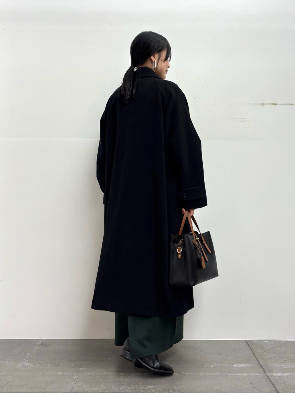 ブラック系のその他アウター、ブラック系のニット/セーター、グリーン系のスカートを着用したレディースの冬コーディネートの3枚目の写真