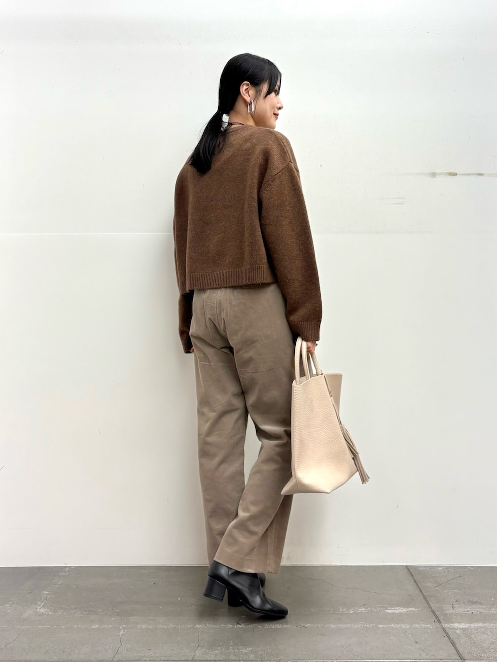 ブラウン系のニット/セーター、ベージュ系のその他パンツ、ホワイト系のトートバッグを着用したレディースの冬コーディネートの3枚目の写真