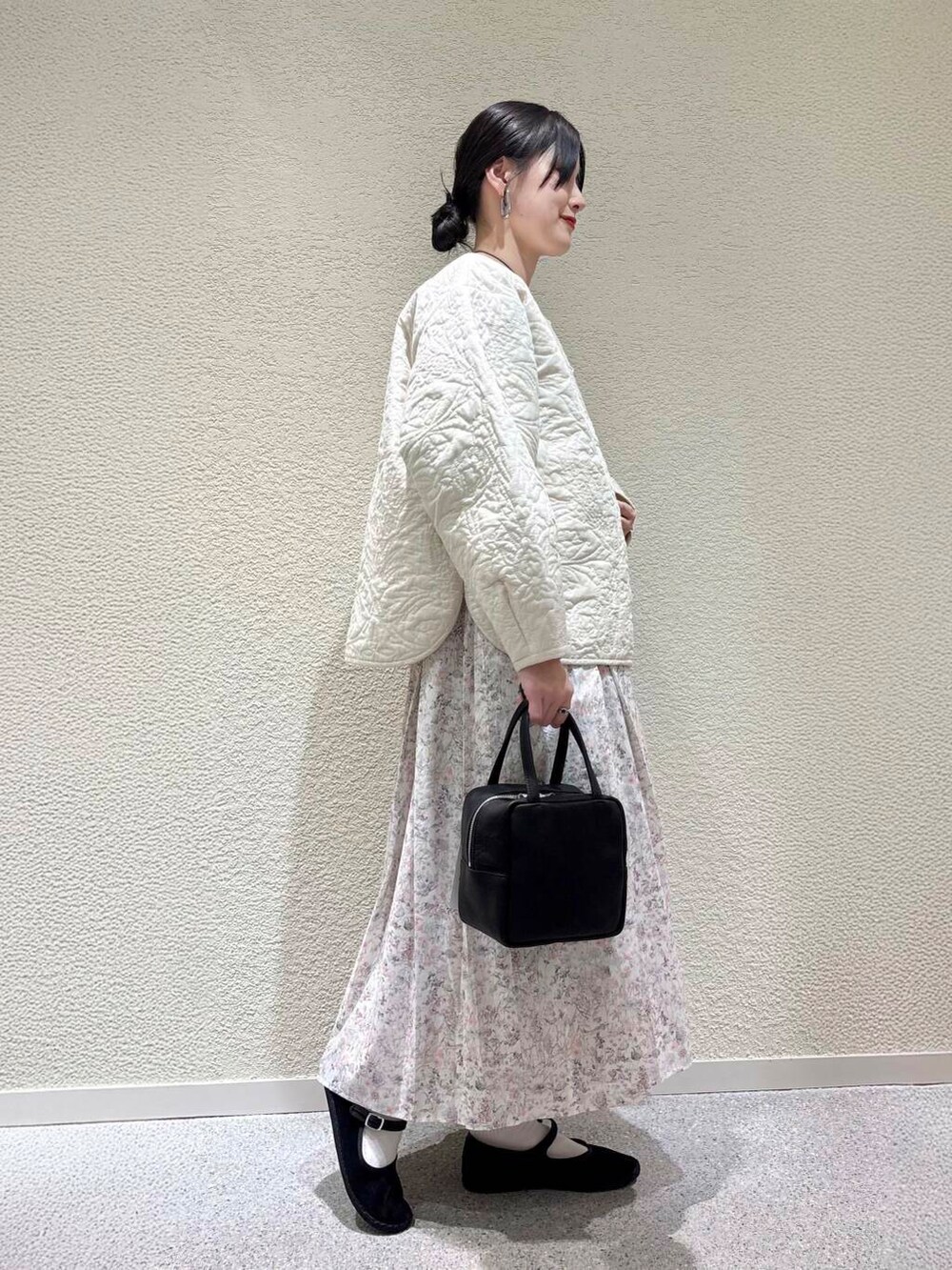 ベージュ系のTシャツ/カットソー、ホワイト系のスカート、ホワイト系のダウンジャケット/コートを着用したレディースの春コーディネートの2枚目の写真