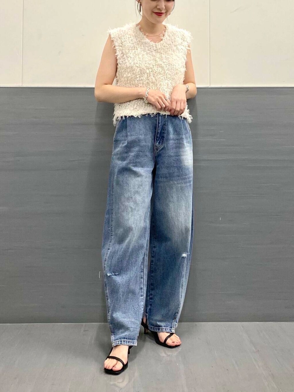 ブルー系のデニムパンツ、ホワイト系のベスト、ブラック系のサンダルを着用したレディースの夏コーディネートの5枚目の写真