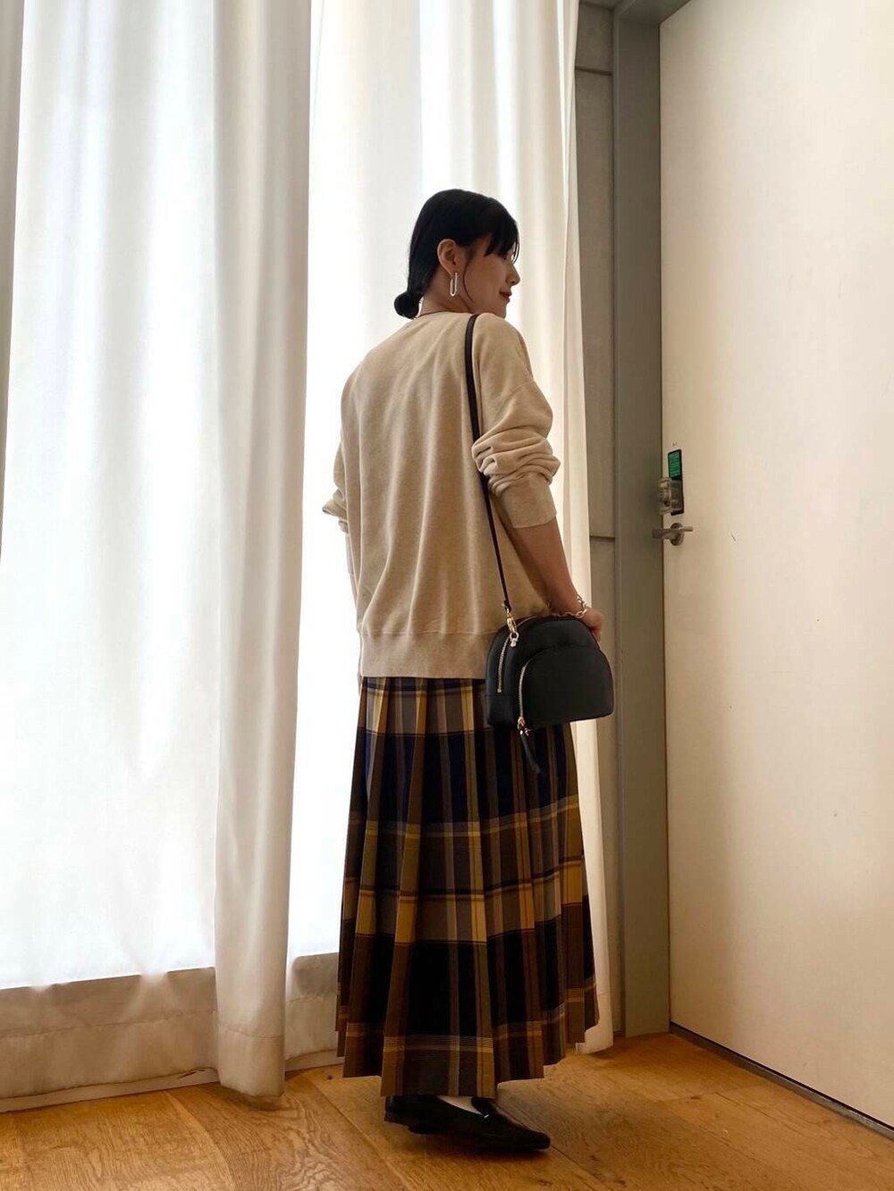 ブラック系のローファー、ブラック系のショルダーバッグ、ブルー系のスカートを着用したレディースの秋コーディネートの4枚目の写真