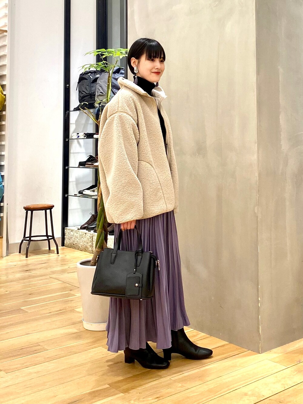ホワイト系のブルゾン、ブラック系のニット/セーター、パープル系のスカートを着用したレディースの冬コーディネートの3枚目の写真