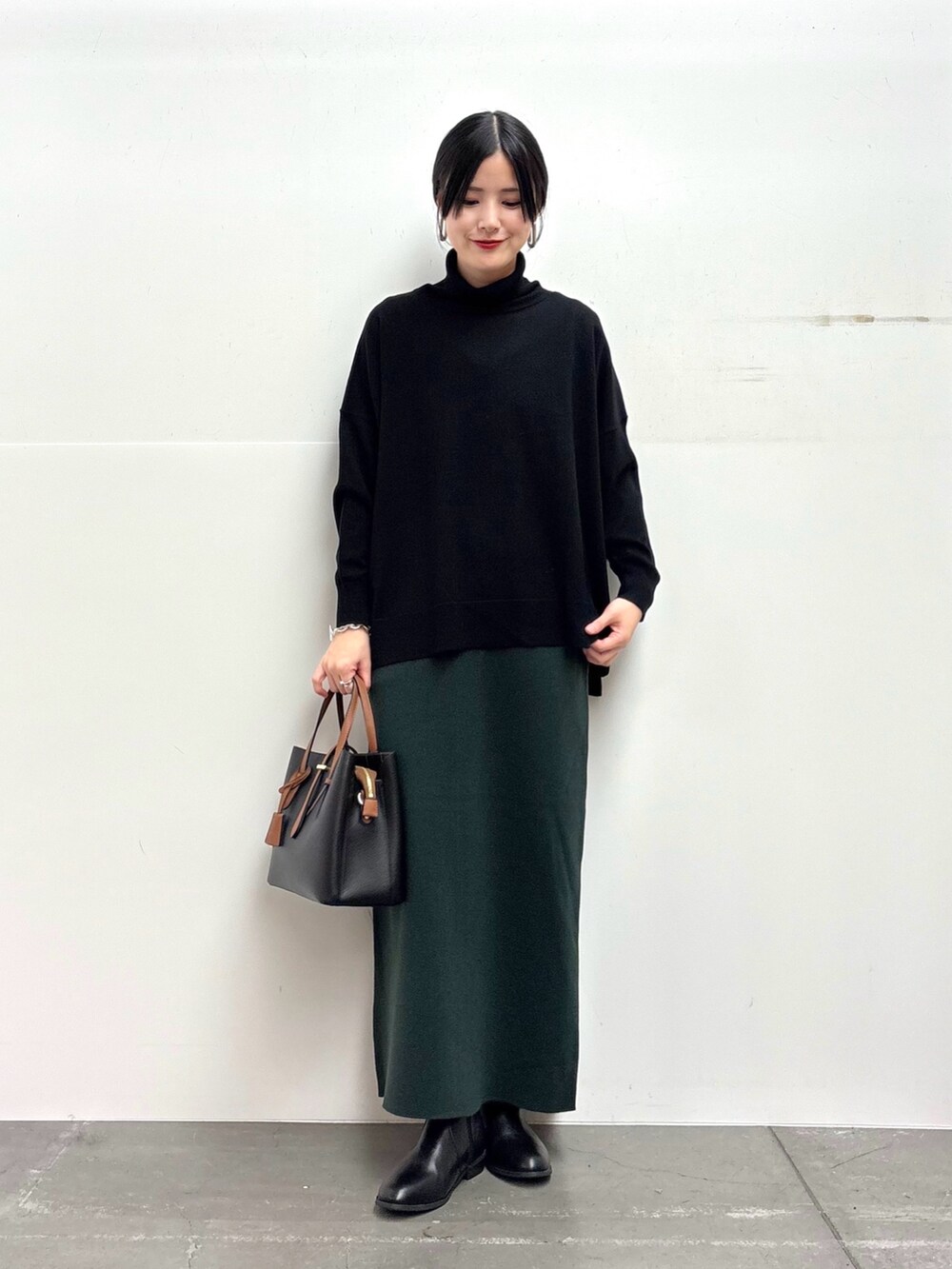 ブラック系のその他アウター、ブラック系のニット/セーター、グリーン系のスカートを着用したレディースの冬コーディネートの4枚目の写真