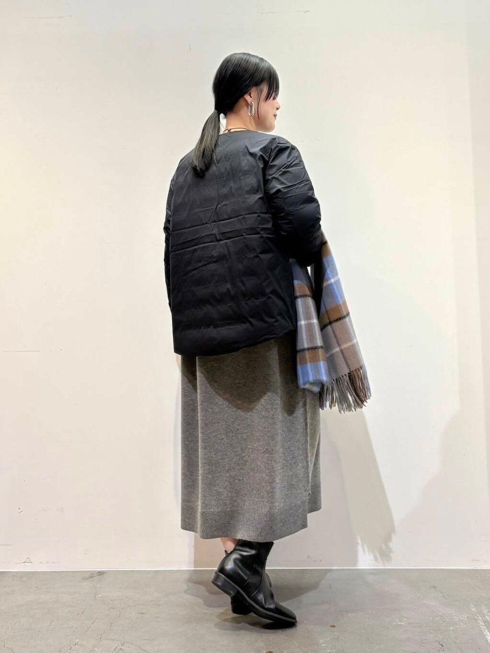 ブラック系のダウンジャケット/コート、ブラック系のブーツ、グレー系のワンピースを着用したレディースの冬コーディネートの3枚目の写真