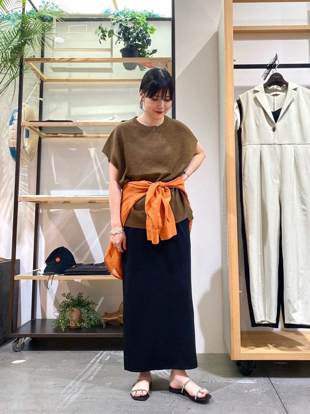ブラウン系のニット/セーター、オレンジ系のシャツ/ブラウス、ブラック系のスカートを着用したレディースの夏コーディネートの3枚目の写真