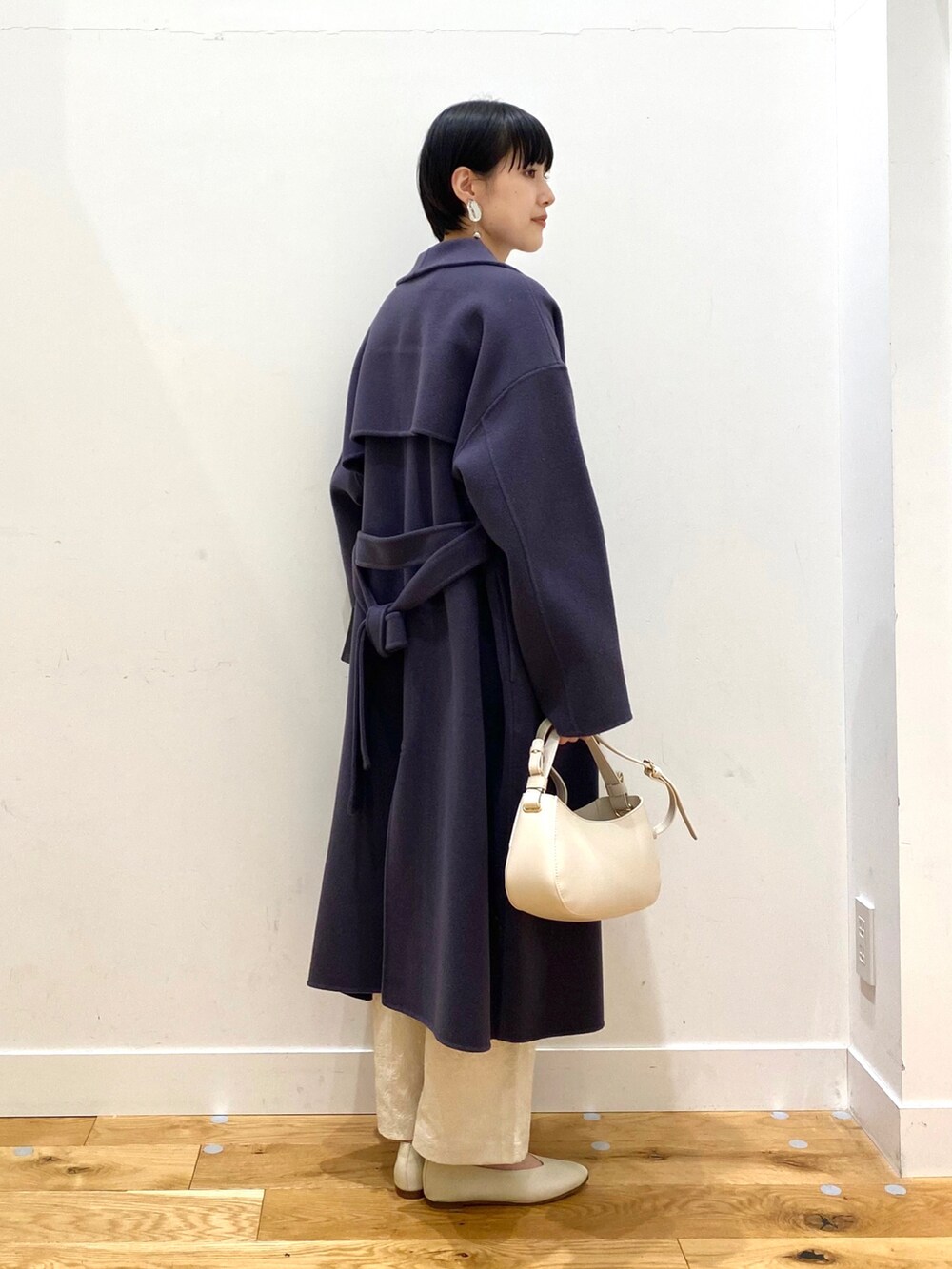 ブルー系のチェスターコート、グレー系のニット/セーター、ホワイト系のその他パンツを着用したレディースの冬コーディネートの3枚目の写真