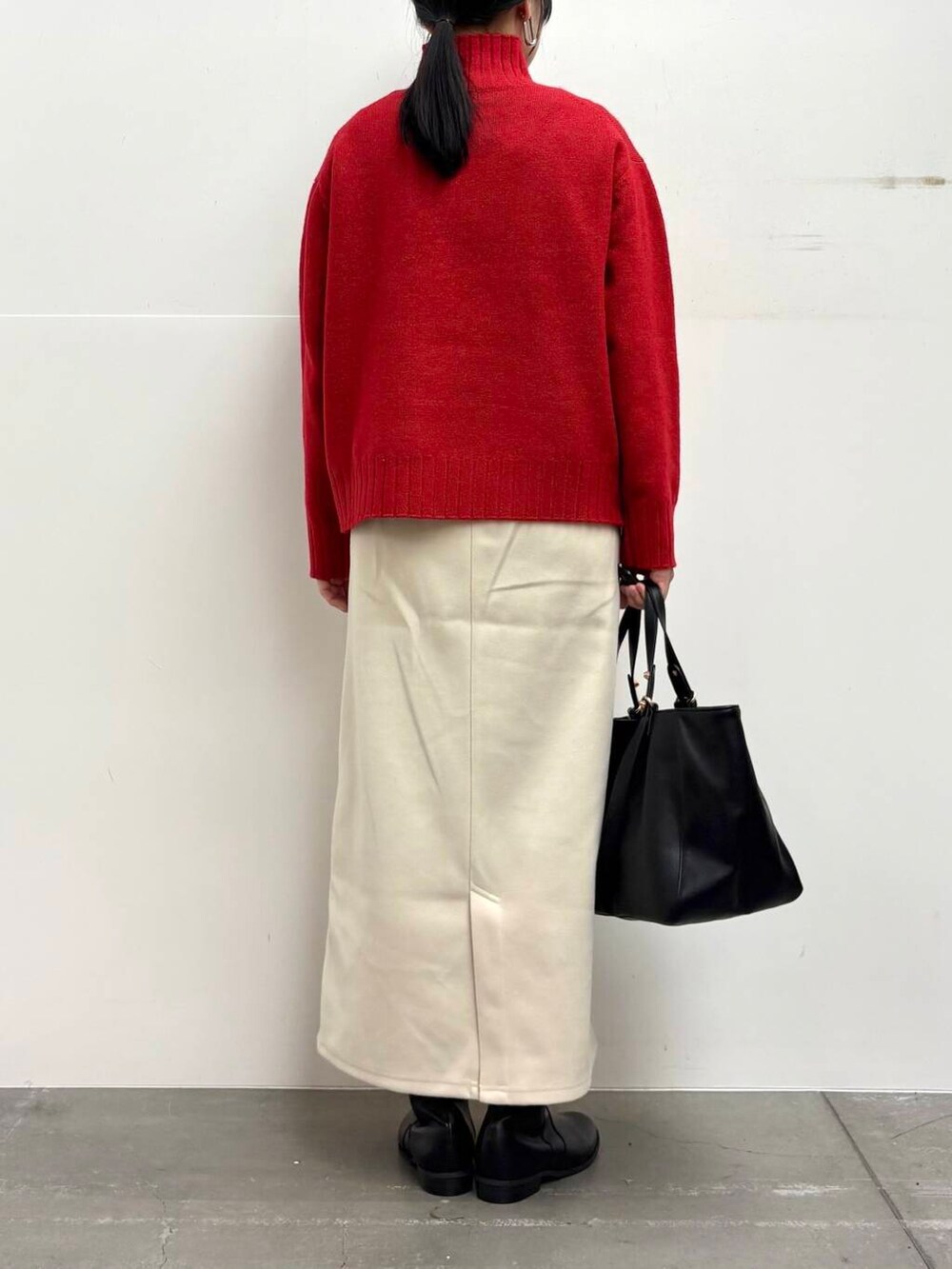 ブラック系のトートバッグ、ブラック系のブーツ、ホワイト系のスカートを着用したレディースの冬コーディネートの5枚目の写真