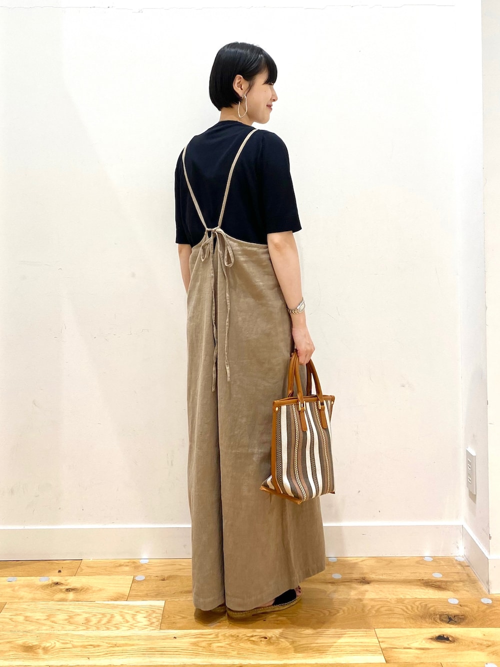 ブラック系のニット/セーター、ベージュ系のサロペット/オーバーオール、イエロー系のトートバッグを着用したレディースの春コーディネートの3枚目の写真