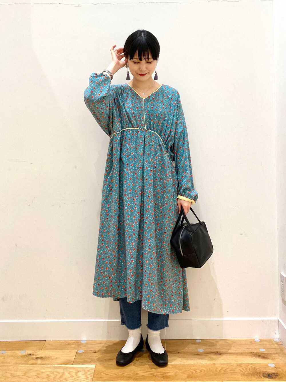 ホワイト系のチェスターコート、グリーン系のワンピース、ブルー系のデニムパンツを着用したレディースの冬コーディネートの3枚目の写真