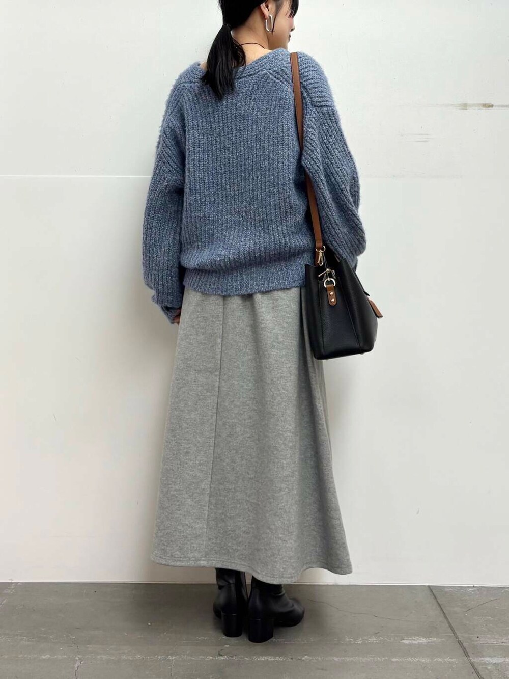 ブラック系のブーツ、ブラック系のトートバッグ、グレー系のスカートを着用したレディースの冬コーディネートの5枚目の写真