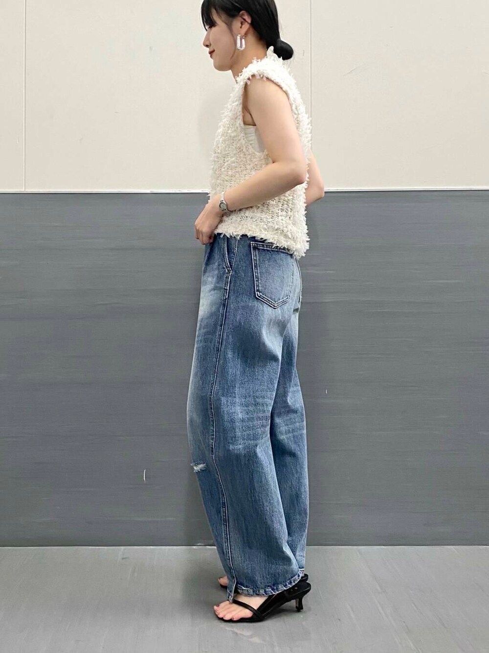 ブルー系のデニムパンツ、ホワイト系のベスト、ブラック系のサンダルを着用したレディースの夏コーディネートの7枚目の写真